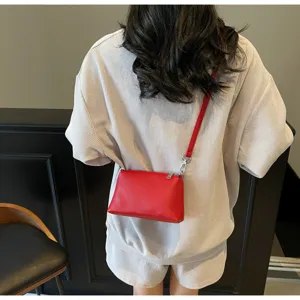Detailed back view of a woman wearing a minimalist red leather crossbody shoulder bag.