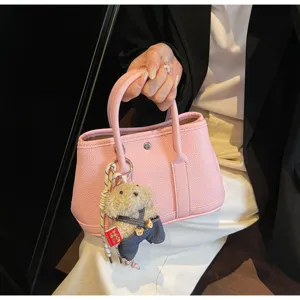 Chic pink leather handbag with cute teddy bear charm, stylish daily tote bag for women.