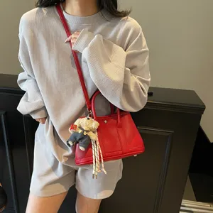 Stylish red leather crossbody bag with cute bear pendant, trendy women's handbag for daily wear.