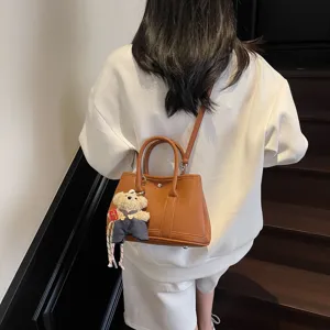Stylish brown leather tote bag with cute bear charm, versatile crossbody handbag for women.
