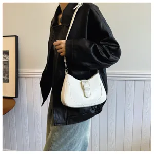 Dettaglio di una elegante borsa a tracolla bianca con design a fibbia di tendenza.