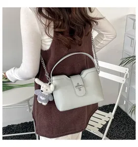 Vue détaillée du sac à bandoulière gris élégant avec chaîne et joli pendentif en peluche.
