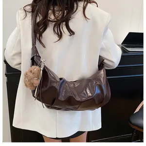 Detail view of a stylish dark brown slouchy dumpling shoulder bag with cute plush bear pendant.