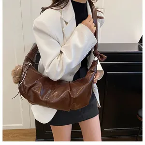 Detailed shot of the brown slouchy shoulder bag with knot strap and cute bear charm.