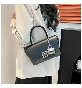 Detailed shot of stylish women black shoulder bag with metal lock charm in indoor scene.