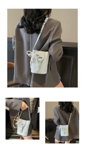 Detail view of a mini bucket bag with pearl lace bow, compact crossbody style for daily use.