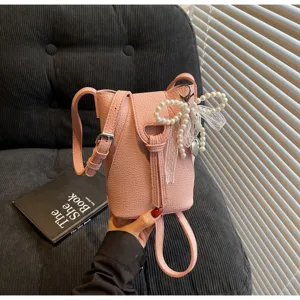 Mini pink bucket crossbody bag with cute pearl bow decor, compact phone purse for daily commute.