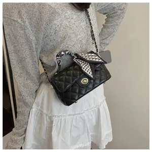 Close-up detail of black quilted leather chain crossbody bag with chic scarf accent.