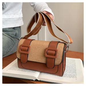 Close-up detail of stylish brown woven straw and leather crossbody satchel bag with buckle.