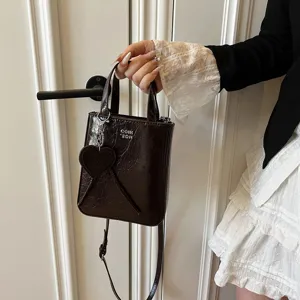 Dark brown patent leather small crossbody bag with heart charm, stylish daily handbag for women.