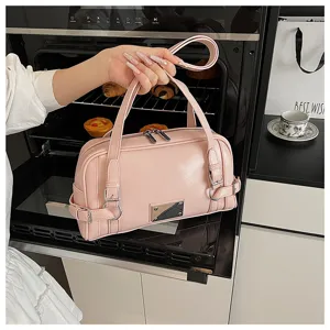 Pink bowling bag for women, stylish PU leather shoulder bag with side buckle details and handles.