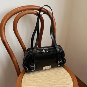 Stylish black glossy bowling bag for women, featuring dual straps and chic silver hardware.