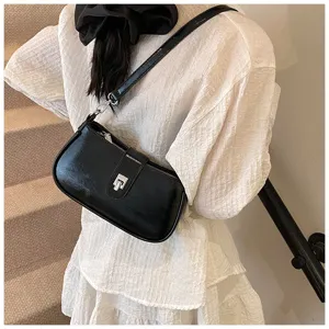 Detailed view of stylish black patent leather underarm shoulder bag with metal lock.