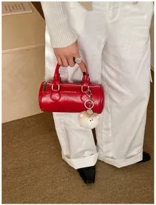 Red cylindrical handbag for women, mini pillow shoulder bag with cute plush sheep charm detail.