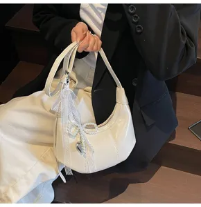White hobo crescent shoulder bag for women with elegant pearl bow pendant and zipper.