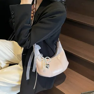 Pink patent leather hobo bag with pearl bow pendant, stylish retro shoulder bag for women.