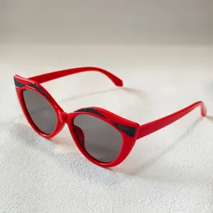 Detailansicht modischer roter Katzenauge Kinder Sonnenbrille mit schwarzem Glitzer-Design.