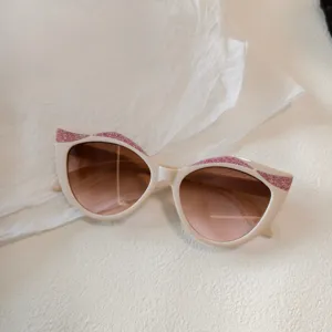 Kinder Sonnenbrille mit Katzenauge, glitzernden Details in Rosa und braunen Gläsern.