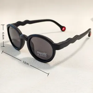 Kids polarized sunglasses detail view, black round frame with wave temples and UV400 protection.