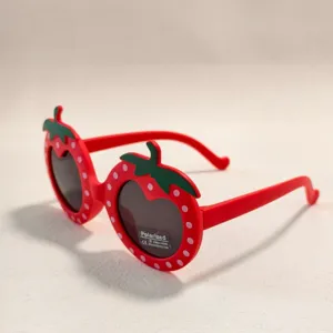 Close-up detail of cute red strawberry shape children polarized sunglasses with green leaves.