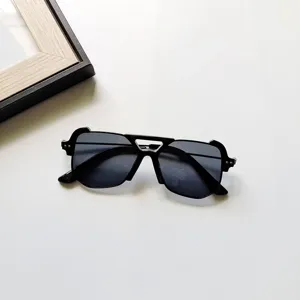 Gros plan sur des lunettes de soleil pour enfants noires au cadre carré et design unique.