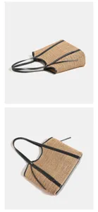 Stro geweven tote tas detail toont textuur, zwart lederen afwerking en dubbele handvatten.