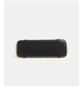 Gedetailleerd overzicht van strooien shopper met zwarte lederen bodem, stijlvol design.