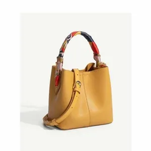 Yellow bucket bag detail view featuring a chic colorful printed scarf wrapped around handle.