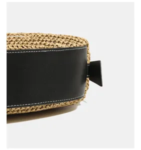 Close-up view of a chic straw woven crossbody bag featuring black leather trim details.