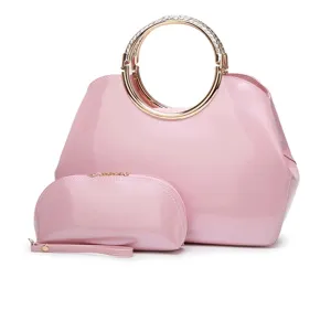 Detalle de bolso de mano de charol rosa con asa de metal y pequeño estuche a juego.