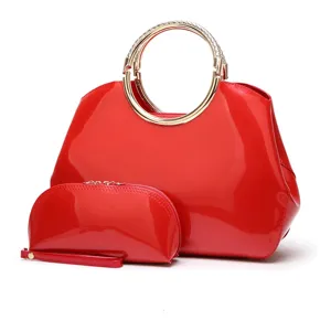 Detalle de bolso de charol rojo con elegante asa de anillo de metal y pequeño bolso a juego.