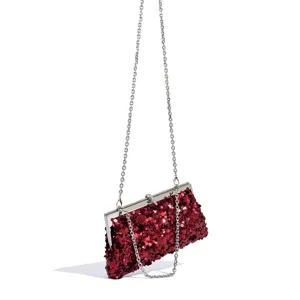 Red sequin clutch bag detail showing sparkling sequins and silver metal chain strap close up.