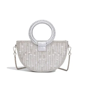 Detailed view of luxury rhinestone half-circle evening bag with pearl decor and silver chain.