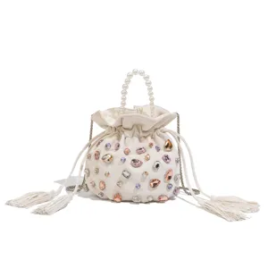 Close-up of a white bucket bag featuring a pearl handle, colorful rhinestones, and delicate tassels.