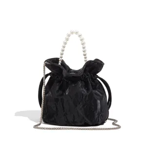 Elegant black velvet bucket bag with pearl handle and stylish silver chain strap accessory.