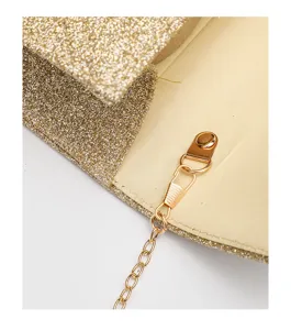 Closeup detail of women gold glitter evening clutch bag featuring metal chain and clasp hardware.