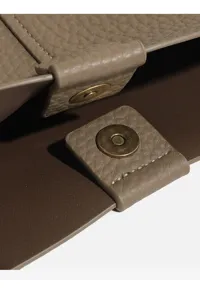 Close-up detail of women handbag magnetic snap closure, premium leather texture hardware.