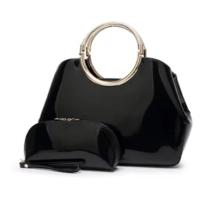 Vista detallada del juego de bolsos de charol negro, elegante asa redonda dorada y estuche.
