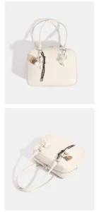 Vista detallada de bolso de hombro retro para mujer en blanco crema con dijes de béisbol.