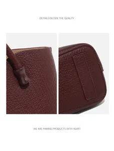 Close-up details of women's burgundy handbag, showing fine leather texture and stitching.