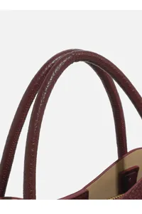 Women's burgundy leather handbag handle detail shot, premium material and fine stitching.