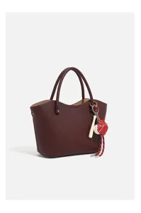 Burgundy textured leather tote bag detail with double handles and baseball keychain.