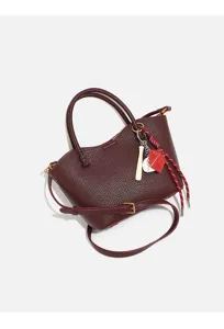 Burgundy pebbled leather crossbody bag detail, featuring stylish handles and charms.