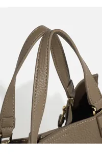 Close-up detail of luxury litchi pattern leather handbag handle and structured gusset craftsmanship.