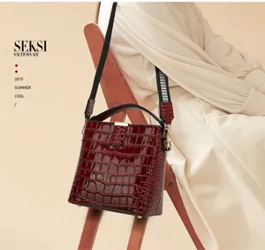 Red patent leather bucket bag with croc embossing, top handle and stylish shoulder strap.