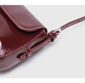 Burgundy patent leather baguette shoulder bag detail, stylish retro flap underarm bag for women.