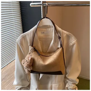 Detailed view of women's chic suede shoulder hobo bag featuring contrast trim and cute plush bear charm.