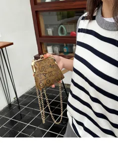 Detail shot of a trendy women kiss-lock chain bag with monogram pattern and gold metal clasp.