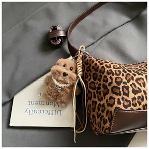Detail shot of the stylish leopard print underarm bag featuring a cute fluffy puppy plush keychain.