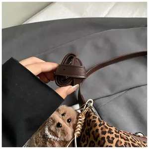 Chic plush dog charm and adjustable leather strap detail of a trendy autumn winter shoulder bag.